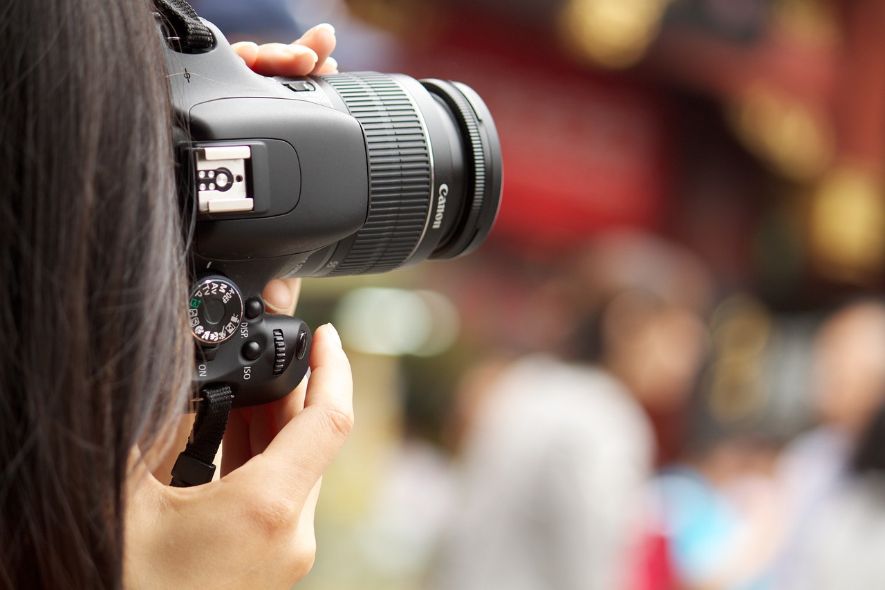 Eventfotograf: So gelingen gute Bilder auch bei schlechtem Licht Eine Person guckt durch eine Fotokamera und knipst ein Bild.